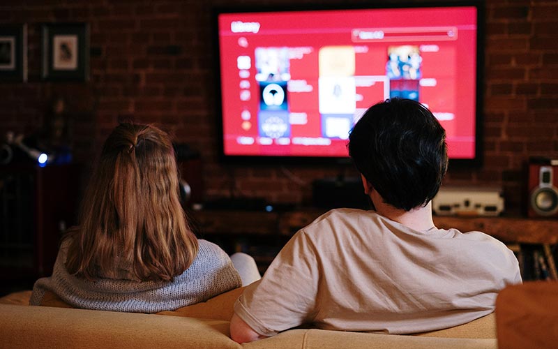 couple watching movie on wall mounted TV